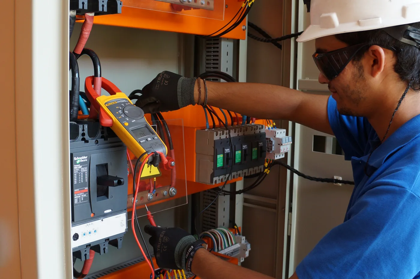 Técnico midiendo con pinza amperimétrica en un tablero eléctrico Schneider